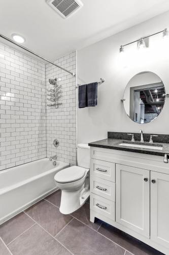 a white bathroom with a tub and a toilet and a sink at Brick & Bed, Riverfront Lofts, PC 206 in Saint Louis