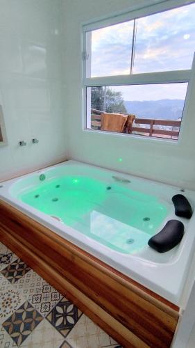 a large bath tub with a window in a bathroom at Mouton Blanc Campos do Jordão in Campos do Jordão