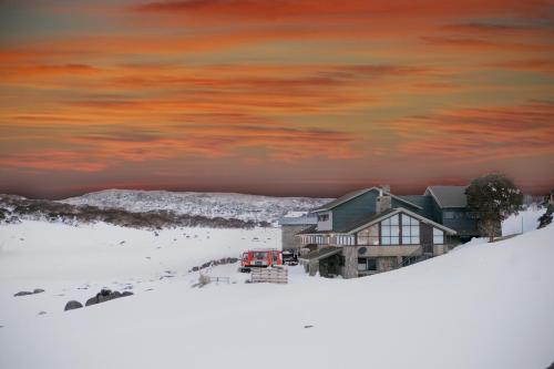 a house in the snow with a red truck in it at Barrakee Ski Lodge in Perisher Valley