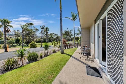 a porch of a house with a table and palm trees at Tasman Holiday Parks - Merimbula in Merimbula
