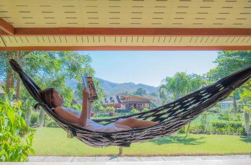 a woman laying in a hammock reading a book at The Nest House in Pai