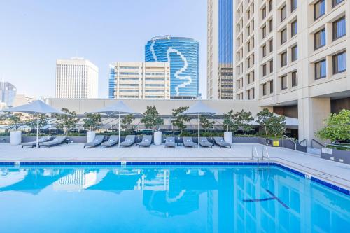 a swimming pool with chairs and umbrellas and buildings at Sofitel Brisbane Central in Brisbane