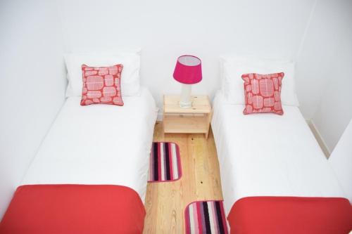 two twin beds in a room with red pillows at Cool Tailor Made 2 Bedroom Apartment in Lisbon