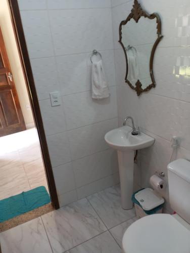 a bathroom with a sink and a toilet and a mirror at Villa Pareto Guest House in Macaé