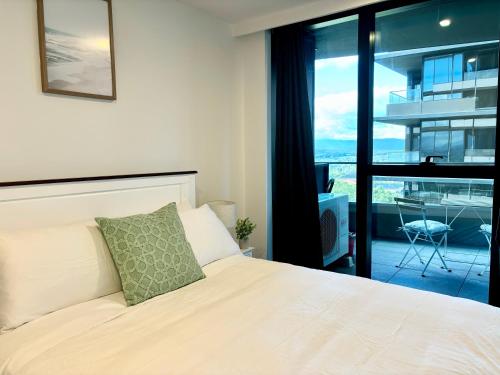 a bedroom with a white bed and a balcony at Skygarden Luxury Condo in Glen Waverley