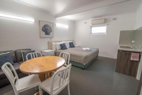 a room with a bed and a table and a couch at Bermagui Motor Inn in Bermagui