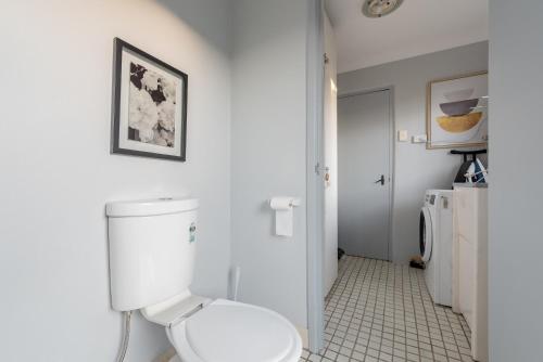 a white bathroom with a toilet and a sink at Bright Single Room - Seconds to Bus Station & Park - Close to Chinatown - Shared Bathroom in Sydney