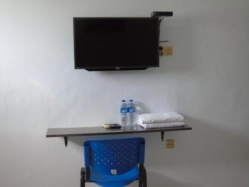 Un escritorio con una silla y un televisor en una pared. en Hotel Permata Zamrud, en Cirebon
