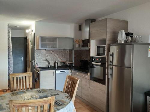 une cuisine avec une table et un réfrigérateur en acier inoxydable dans l'établissement T2 Cabine avec Terrasse et Parking - Le Barcarès - FR-1-195-109, au Barcarès