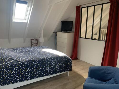 une chambre avec un lit, une télévision et une chaise dans l'établissement Maison Enfants Bienvenue, à 100m Plage, Jardin, WiFi, Parking, Terrasse & Équipements Complets - FR-1-465-113, à Merville-Franceville-Plage