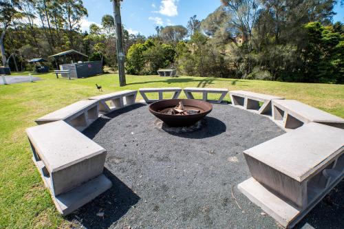 a group of benches in a park with a fire pit at Tasman Holiday Parks - Merimbula in Merimbula