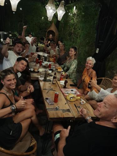 a group of people sitting around a wooden table at Cafe Moto Hostel in Puerto Princesa City
