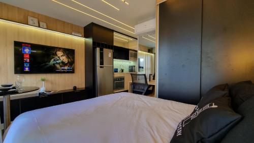 a bedroom with a white bed and a kitchen at Quad Studios by Romastay in Sao Paulo