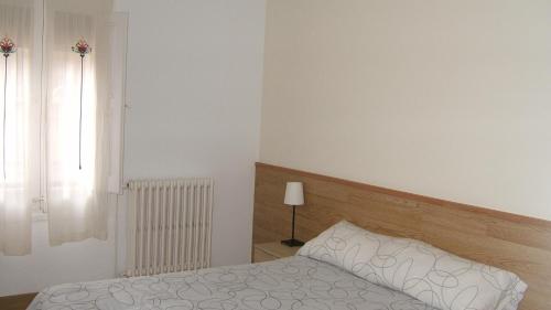 1 dormitorio con cama, lámpara y ventana en Hostal L'Esquella, en Aiguafreda