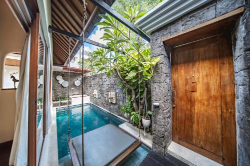 uma casa com uma piscina e uma porta de madeira em Ini Vie Villa Legian by Ini Vie Hospitality em Legian