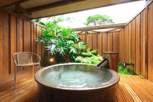 un bain à remous sur une terrasse en bois avec une chaise dans l'établissement Kagetsutei, à Shimoda