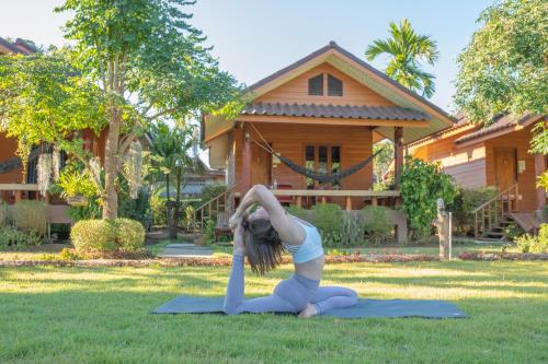 una mujer haciendo una pose de yoga delante de una casa en The Nest House Pai, en Pai