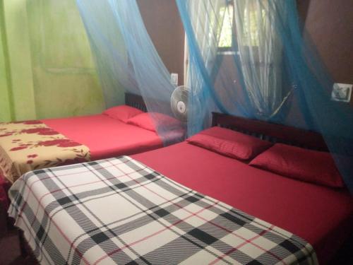 two beds in a room with red and white sheets at Nature Hub Ella in Ella