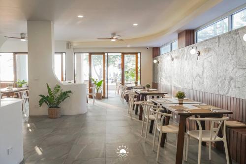 a restaurant with wooden tables and chairs and windows at Talay Hotel and Villa Cha-am in Cha Am