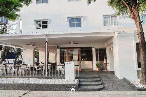 a white building with tables and chairs at Talay Hotel and Villa Cha-am in Cha Am