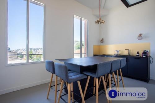 une cuisine avec une table noire et des chaises bleues dans l'établissement Apartment T3 air-conditioned in house neighborhood Cimiez, à Nice