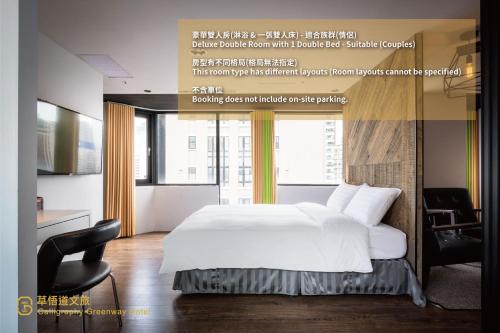 um quarto com uma grande cama branca e uma cadeira em Calligraphy Greenway Hotel em Taichung