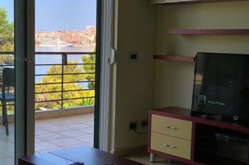 d'un salon avec une télévision et une vue sur un balcon. dans l'établissement Beachfront Apartment - Sarandë, à Saranda