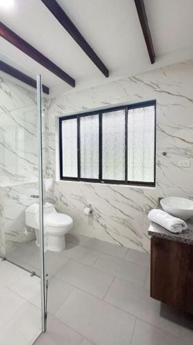 a bathroom with a toilet and a sink and a window at Doral House Villavicencio in Villavicencio