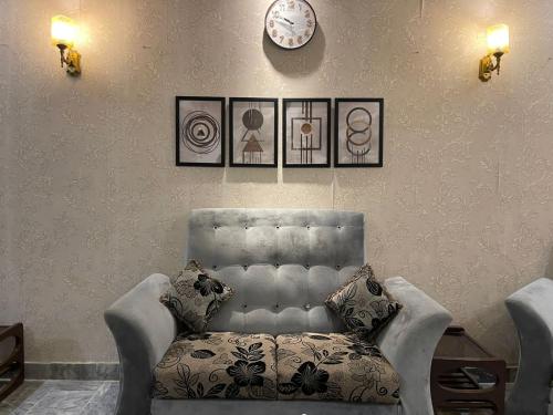 a living room with a chair and a clock on the wall at Travellers Home 2BR PORTION Gulshan Iqbal blk#7 in Karachi