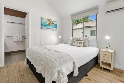 a white bedroom with a large bed and a window at Tasman Holiday Parks - Airlie Beach in Airlie Beach