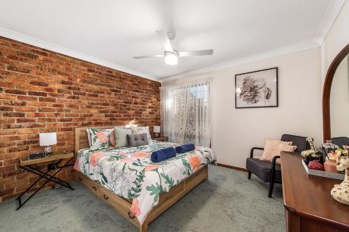 a bedroom with a bed and a brick wall at 29A Ballina Crescent Port Macquarie in Port Macquarie