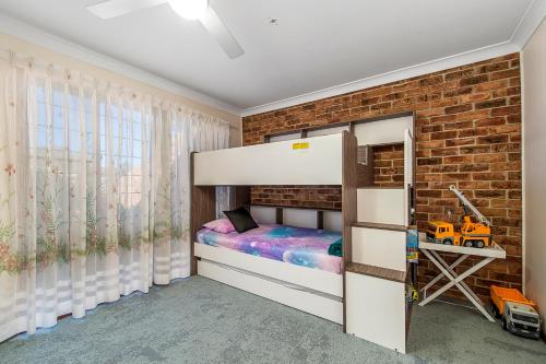a bedroom with a bunk bed and a brick wall at 29A Ballina Crescent Port Macquarie in Port Macquarie