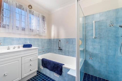 a blue tiled bathroom with a tub and a shower at 29A Ballina Crescent Port Macquarie in Port Macquarie