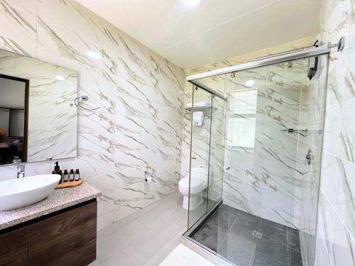 a bathroom with a glass shower and a sink at Doral House Villavicencio in Villavicencio