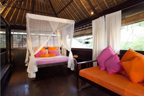 ein Schlafzimmer mit einem Himmelbett und einem Sofa in der Unterkunft Chai House in Ubud