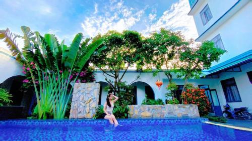a woman sitting on the edge of a swimming pool at Tropical Homestay Phu Yen in Tuy Hoa