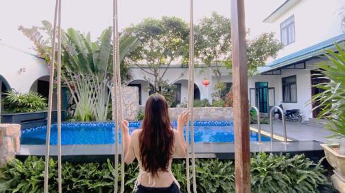 a woman sitting on a swing in front of a pool at Tropical Homestay Phu Yen in Tuy Hoa