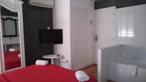 uma casa de banho com banheira e uma televisão na parede em Hotel Le 5 em Martigues