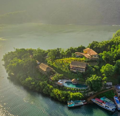 eine Insel mit Häusern und Booten im Wasser in der Unterkunft Mai Chau Hideaway Lake Resort in Mai Châu