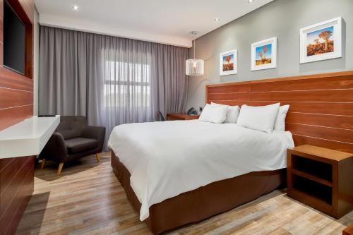 Pokój hotelowy z dużym łóżkiem i krzesłem w obiekcie Protea Hotel by Marriott Pretoria Hatfield w mieście Pretoria