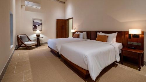 a hotel room with two beds and a chair at Sanhe Daoli Resort in Qingyuan