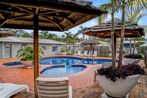 a swimming pool with chairs and umbrellas at BIG4 Tasman Holiday Parks - Tathra Beach in Tathra