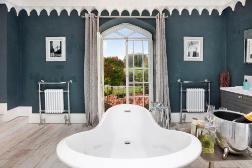 a bathroom with a large white tub in a blue wall at Colleton Hall in Rackenford