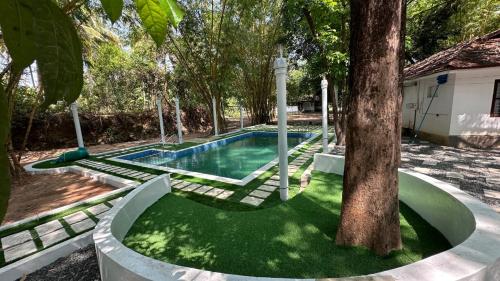 a swimming pool with a tree in a yard at Surya Eco and Wedding Resort in Trichūr
