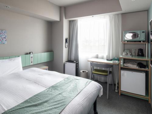a bedroom with a bed and a desk and a tv at Vessel Inn Takadanobaba Ekimae in Tokyo