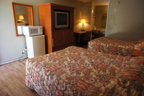 a hotel room with two beds and a tv at Executive Inn & Suites in Orange