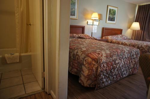 a hotel room with two beds and a bathroom at Executive Inn & Suites in Orange