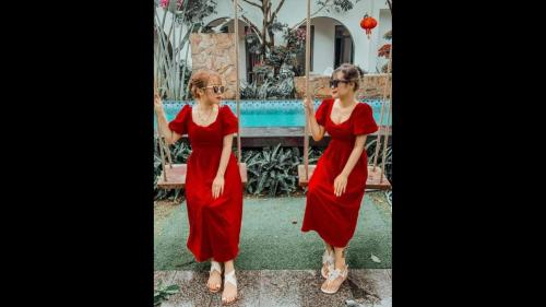 Una donna con un vestito rosso in piedi davanti a una piscina di Tropical Homestay Phu Yen a Tuy Hoa