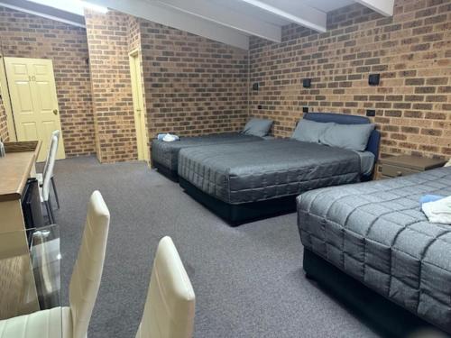 a room with two beds and a brick wall at Clock Tower Motor Inn in Coonabarabran
