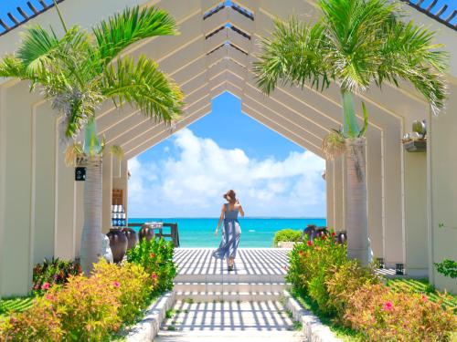 a woman walking through an archway with the beach in the background at Haimurubushi in Kohama